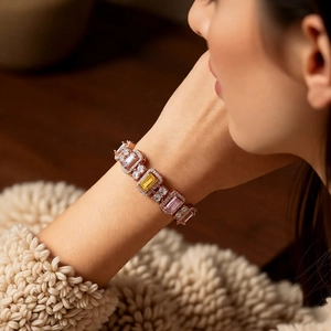 Detail of elegant rose gold bracelet with colorful square zircons on model's wrist