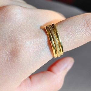 Detail of triple-layer gold ring showing polished and frosted stainless steel textures