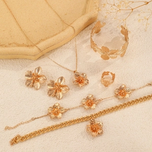 Detailed set of gold floral jewelry including necklace, bracelet and ring on stone props