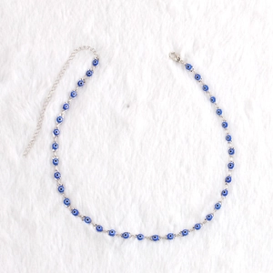 Detail view of Evil Eye charm anklet on white plush background with lobster clasp