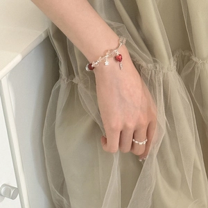 Fresh glass bead strawberry bracelet and fine diamond ring on elegant mesh background