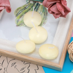 Close-up of four cream yellow floating candles arranged with dried pink flowers on a frame