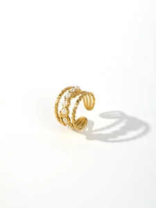 Macro detail of multilayer gold-plated ring with elegant white pearl inlays