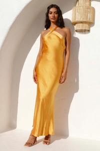 Detailopname van de gele satijnen halterjurk textuur en open rug silhouet hier