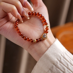 Detail of garnet beaded bracelet with a gold heart pendant on a woman's wrist