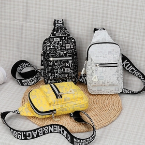 Detailed display of colorful letter print chest bags with triangle charms on grass mat