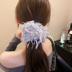 Détail d'un chouchou en plumes violet clair porté sur cheveux longs pour un look élégant