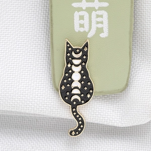 Detailed macro view of black enamel cat brooch with gold lunar phase and star patterns
