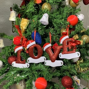 Sparkly red LOVE alphabet Christmas ornaments with Santa hats hanging on a tree