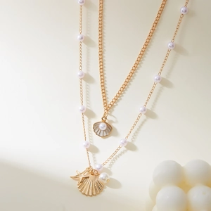 Close-up of gold layered necklace with pearls, seashells, and starfish charms