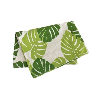 Set de table en lin plié avec motif de feuilles de monstera vertes sur fond crème