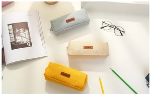 Flat lay of rectangular canvas pencil cases in grey, beige, and yellow on a desk