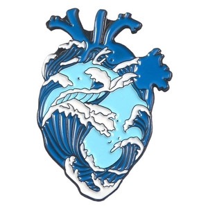 Detail of heart-shaped enamel pin featuring blue and white wave ocean art patterns