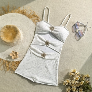 Close-up of white one-piece swimsuit with textured fabric and gold sun metal accents