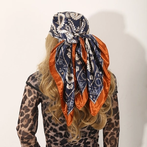 Rear view of a navy blue paisley satin scarf worn as a headscarf with orange border