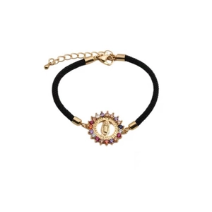 Detailed macro view of gold Virgin Mary charm with colorful cubic zirconia on black cord