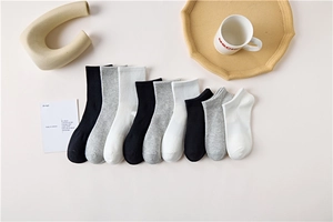 Flat lay of cotton crew socks in black, grey, and white with minimalist lifestyle props