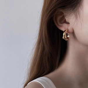 Minimalist gold hoop earrings with irregular hammered texture on a female model