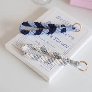Detail of handmade woven wristlet keychains in blue and white stripes with gold rings