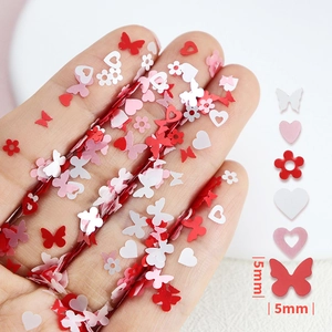 Macro view of 5mm pearlescent heart and butterfly nail art sequins in pink and red