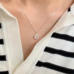 Close-up of a rose gold smiley face necklace with a clear zircon pendant on a model's neck