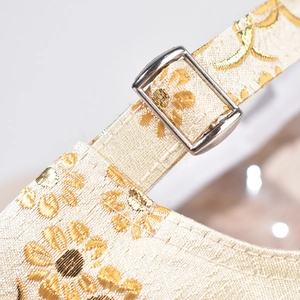 Macro shot of gold floral jacquard strap with polished silver metal buckle detail