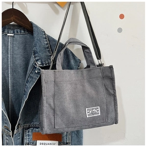 Gray corduroy crossbody bag hanging next to a denim jacket in a bright lifestyle setting