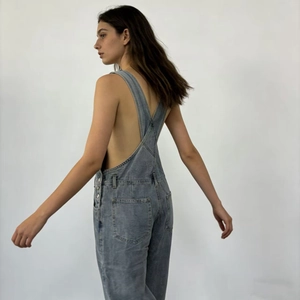 Detail view of denim overalls with criss-cross back straps and functional large pockets