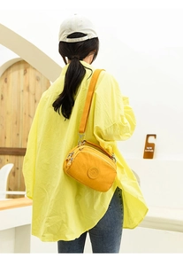Detailed view of the yellow nylon crossbody bag with adjustable strap and zip layers