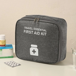 Portable gray oxford fabric travel first aid kit with zipper and carry handle on desk