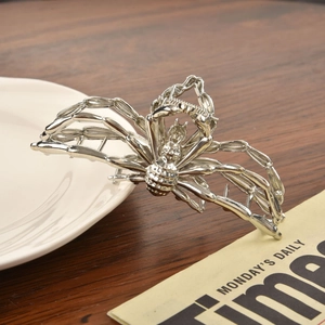Detailed view of silver alloy spider hair claw clip with metallic finish on white ceramic