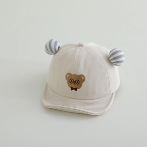 Detail of baby sun hat with brown bear embroidery and striped soft poms on peak