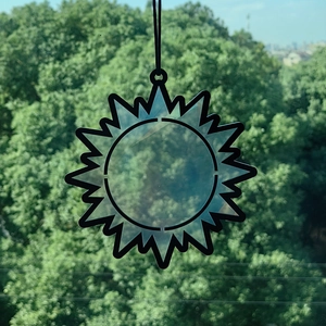 Detail of sun-shaped prism crystal suncatcher with black outlines for window decor