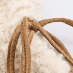 Detailed close-up of soft beige faux shearling fabric with brown suede drawstring texture