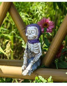 Detalle de figura de esqueleto pescando con pañuelo morado para jardín o pecera decor