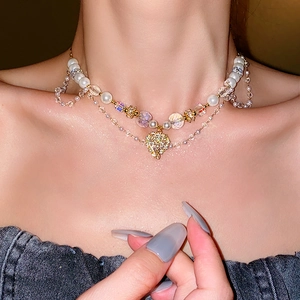 Close-up of double-layered pearl and crystal necklace with golden heart pendant