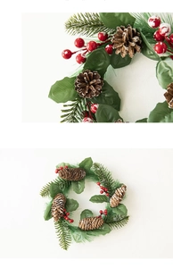Detail of Christmas wreath featuring red berries, green pine needles and natural pinecones