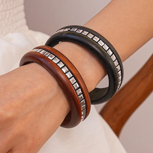 Gros plan de bracelets en bois vintage avec clous carrés en métal sur un poignet
