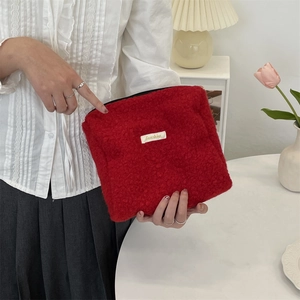 Gedetailleerde weergave van de rode boucle fleece make-up tas met Sunshine-label.