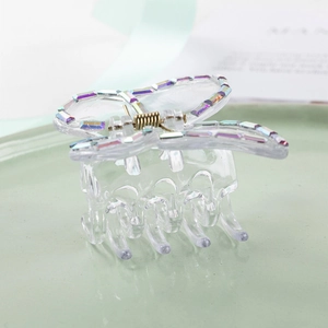 Pince à cheveux papillon transparente élégante avec strass colorés sur plat céramique