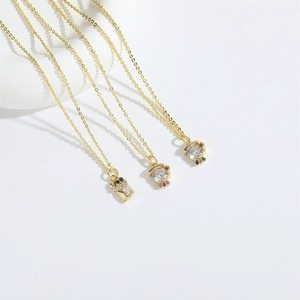 Three gold necklaces with crystal doll pendants and colorful stones on a white background