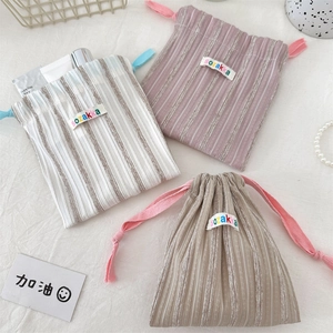Close-up of striped drawstring storage pouches with woven ropes and brand labels