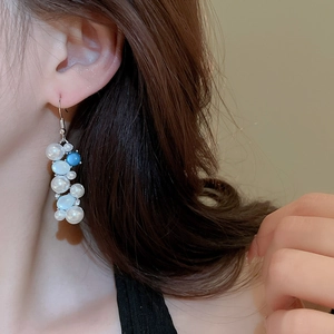 Detailed view of elegant drop earrings featuring white pearls and a sky blue accent bead