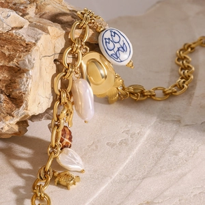 Collier doré avec perle baroque, pendentif céramique et breloques marines sur pierre
