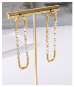 Macro view of gold U-shaped earrings featuring a row of clear cubic zirconia stones