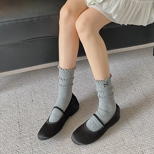 Detail of grey ruffled socks with black bow embroidery paired with Mary Jane shoes