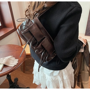 Detail of a dark brown bow shoulder bag with pleated texture on a vintage background