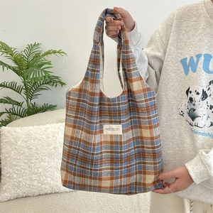Close-up of retro plaid wool tote bag with brand label in a cozy home setting