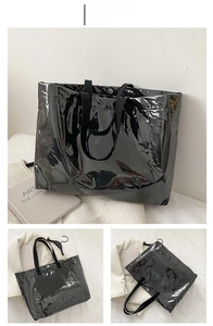 Close-up of black glossy tote bag with Skillfully logo and durable woven shoulder strap