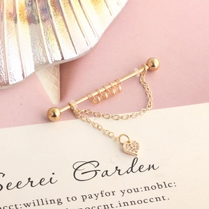 Macro detail of a golden industrial barbell with chain and heart cubic zirconia pendant